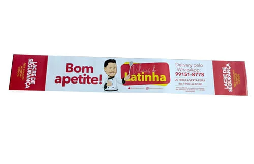 Rótulo Adesivo Personalizado da Marca "Delícias da Latinha" tem o desenho de um homenzinho de roupa de cozinheiro e uma colher na mão, também está escrito "bom apetite" e "lacre de segurança" no rótulo. O rótulo está ligeiramente em pé, sendo possível ver todas as informações.