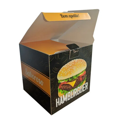 caixa Hamburguer Personalizada, a cor predominante é preta, com uma textura de hambúrgueres desenhados em amarelo. Na face a esquerda é possível ver uma tira em amarela com o escrito "saboroso" em branco e na face a direita uma foto de um lanche com a palavra "hambúrguer" abaixo, é possível ver que a caixa está aberta, as orelhas da caixa são amarelas e na lingueta da tampa é escrito "bom apetite!" na cor preta.