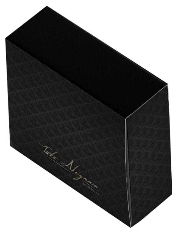 Uma caixa cinza chumbo com arabescos pretos, ela se assemelha a uma caixa de fósforos e tem um logotipo escrito a mão em dourado "Tati Negrão Semijoias"