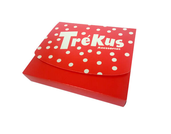 Embalagem retangular na cor vermelha, com uma tampa com detalhes de bolinhas brancas e o logotipo "Trékus Acessórios".