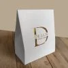 Caixa Presente Personalizada, branca com hotstamping dourado. Sobre uma mesa de madeira.