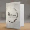 Pasta Personalizada com Orelha para consultório com uma dobra na cor branca com detalhes cinza com a logo "dr willian" ao centro, fundo cinza na mesa madeira