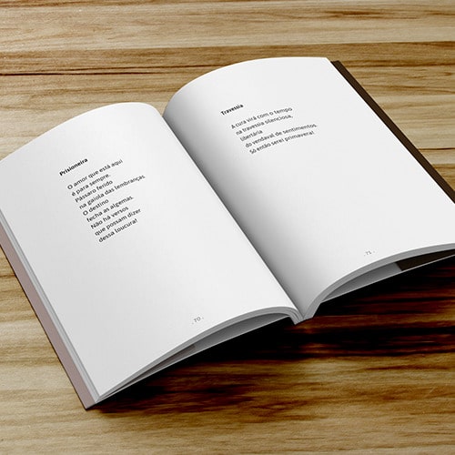 Livro com capa com laminação fosca e verniz localizado, aberto, mostrando o miolo impresso na cor preta. O livro está sobre uma mesa de madeira.
