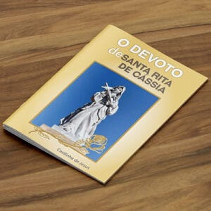 Livro com lombada canoa e grampo. Vemos um livro com pouco páginas, capa colorida predominantemente amarela com a imagem de Santa Rita de Cássia com título 