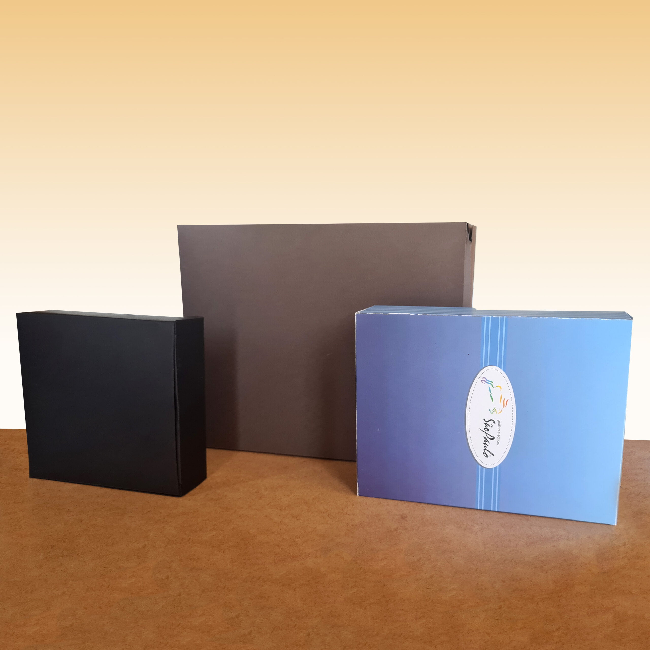 Caixa para Cartucho Presente Personalizado, três caixas sobre uma mesa marrom ao fundo dourado